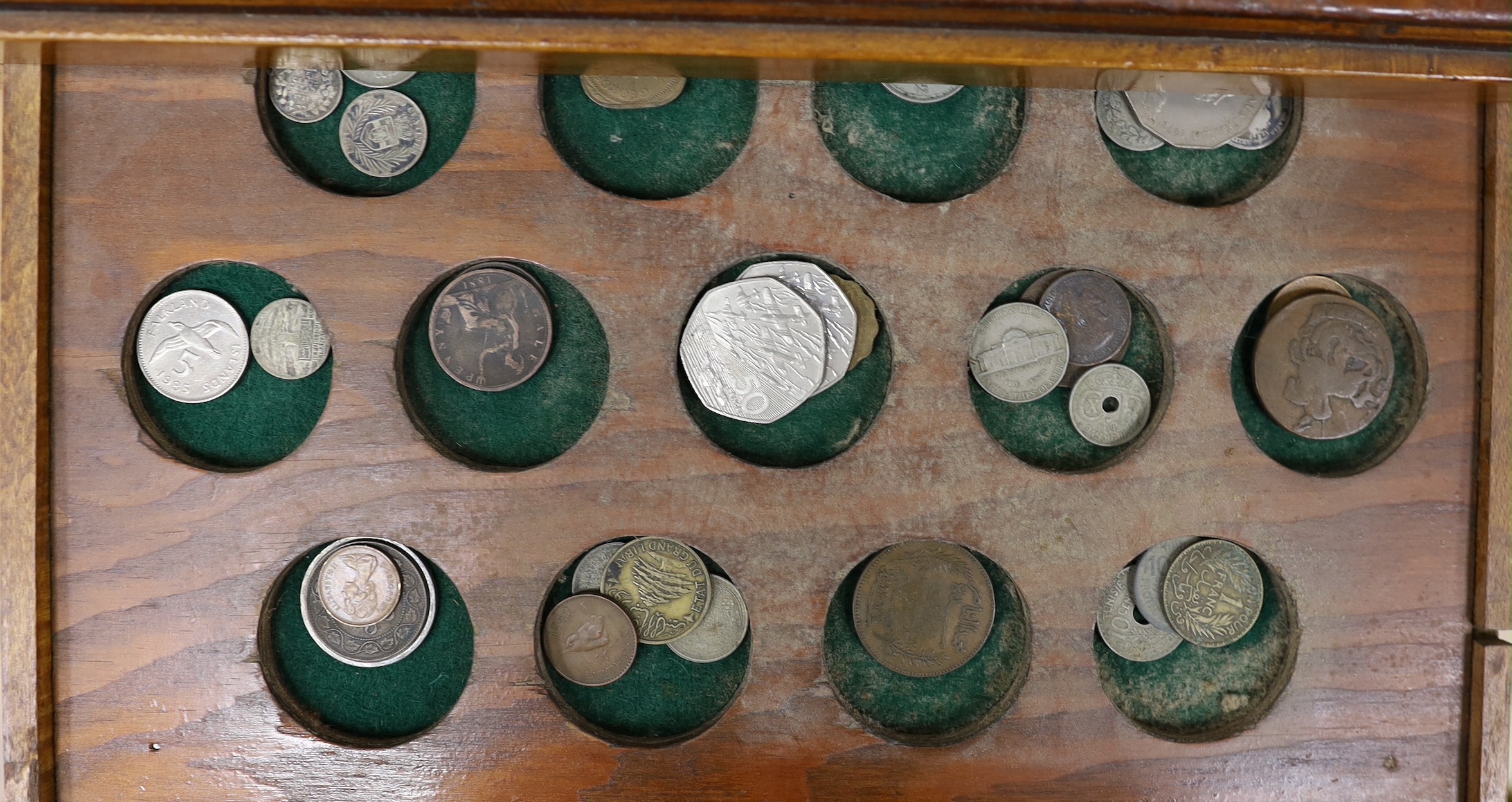 A collection of mixed coinage in a collectors cabinet, 27cm tall